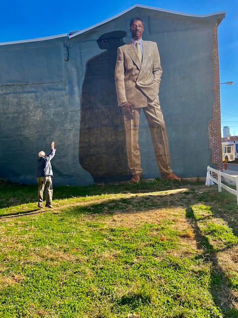 Victor Mair shooting a basketball toward a mural of Julius Erving